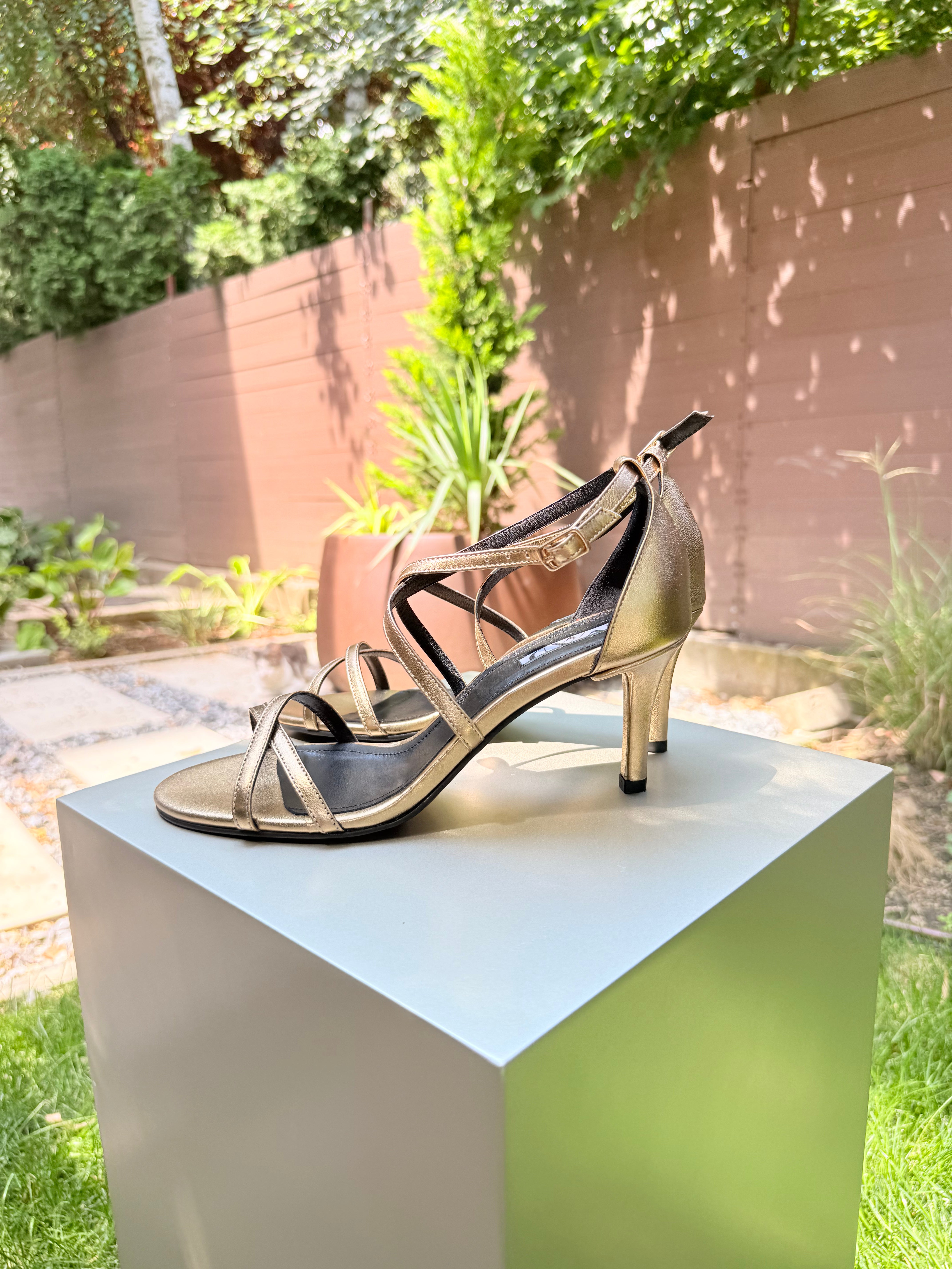 Gold leather heeled sandal with open toe, classic stiletto heel, and crisscross straps