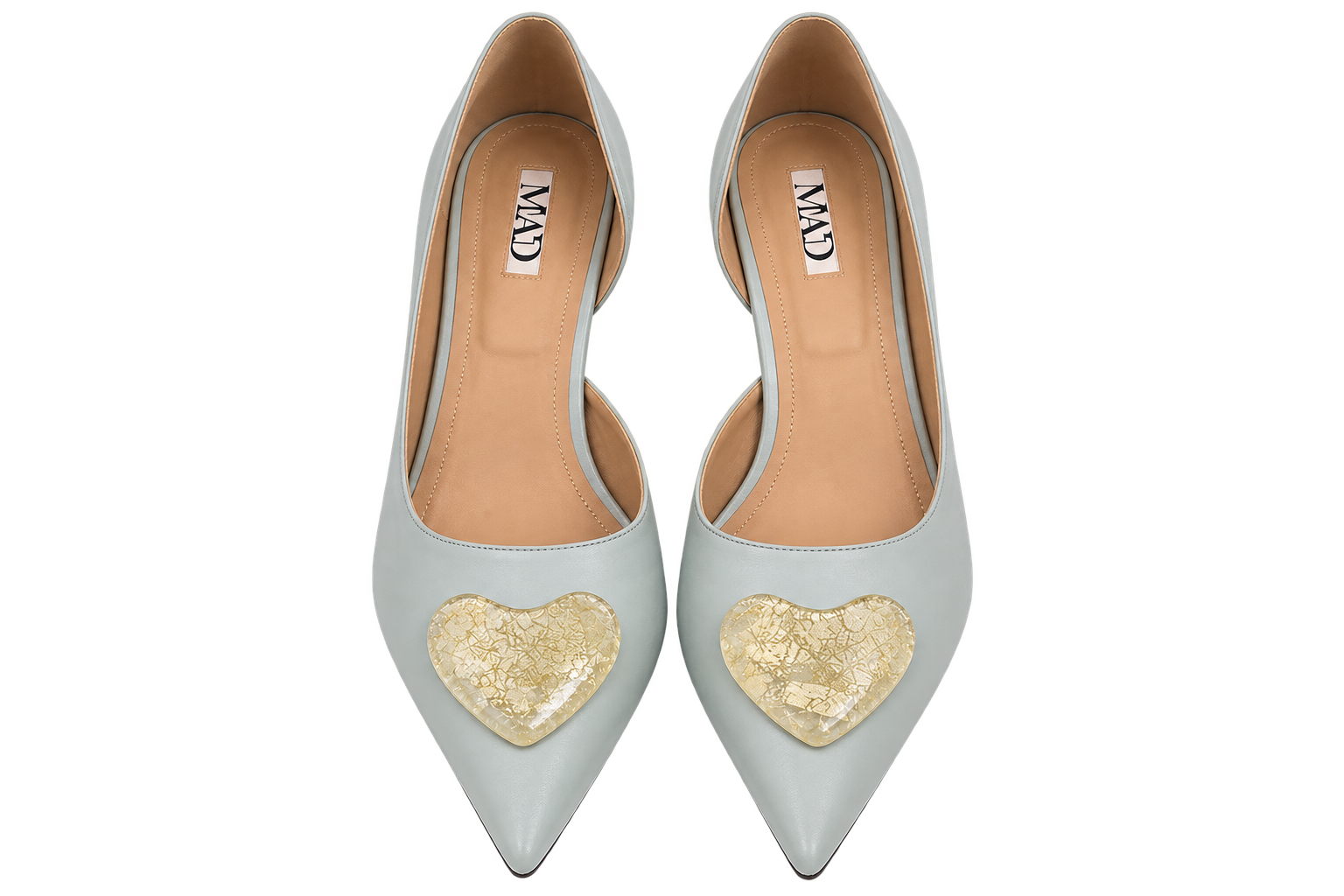 A pair of pointed-toe pumps in a pale icy blue-gray color, featuring a textured gold heart patch on the toe area. The shoes are shown from a top-down view on a solid white background, with the brand name 'MAD' visible on the insoles.