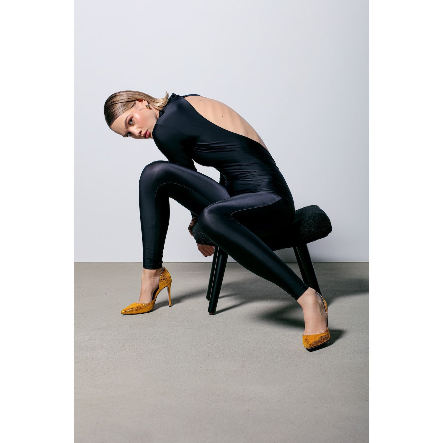 model wearing black suit and gold leather stilettos